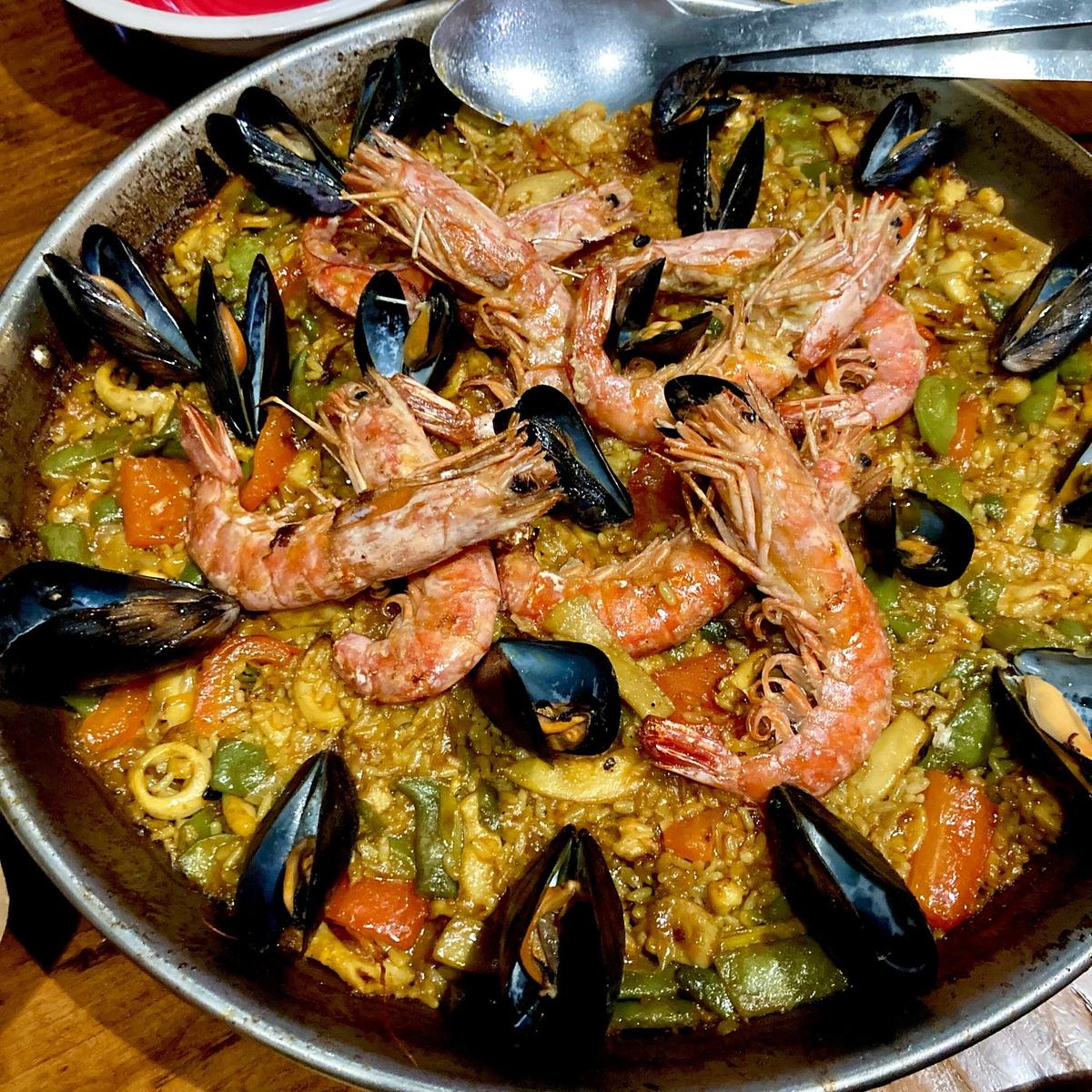 Paella de marisco con gamberoni, cozze e vongole nella paellera, su un tavolo di El Prado