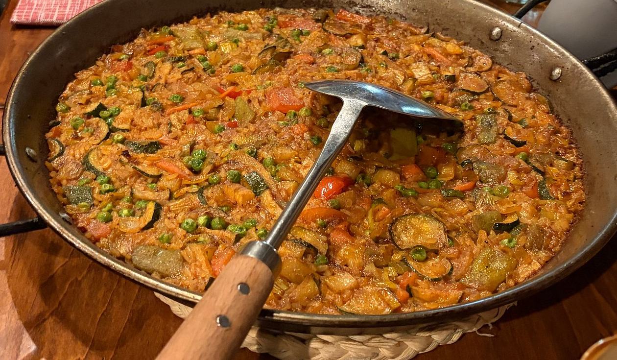 Paella vegetariana con zucchine e piselli nella paellera